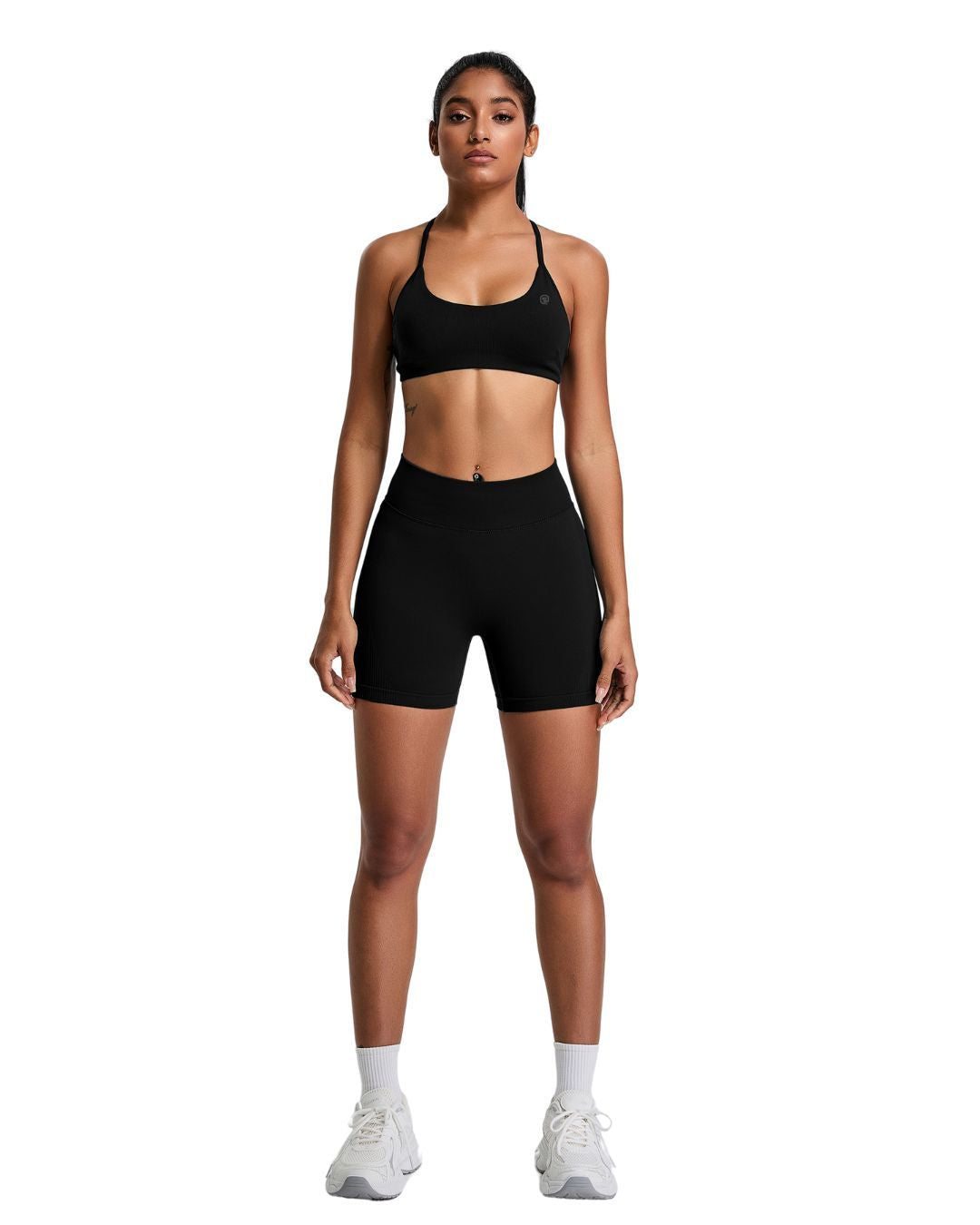 Woman wearing black ORU Elura short with high-rise waistband and sports bra standing against white background