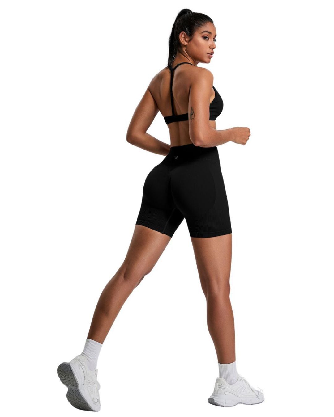 Woman wearing black ORU ELURA SPORTS BRA with T-shape back and matching black shorts in activewear pose
