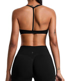 Back view of woman wearing black ORU Elura sports bra with T-shape strap and matching leggings