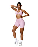 Woman wearing pink ORU Mika halter sports bra with halter neck support and matching shorts, styled for fitness or casual wear