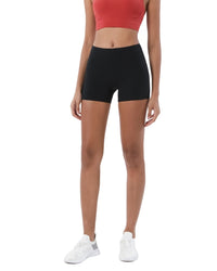 Woman wearing black ORU Mid-Rise Yoga Shorts with a red sports bra and white sneakers