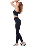 Woman wearing black ORU COZY POCKET LEGGINGS with side pockets and black sports bra, stretching pose