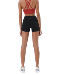 Back view of woman wearing black ORU Mid-Rise Yoga Shorts with slim fit and subtle glute contour