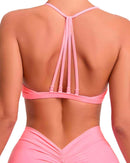 Back view of a woman wearing a pink ORU strappy sports bra with multiple thin straps and a smooth, lightweight, high-impact design.