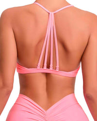 Back view of a woman wearing a pink ORU strappy sports bra with multiple thin straps and a smooth, lightweight, high-impact design.