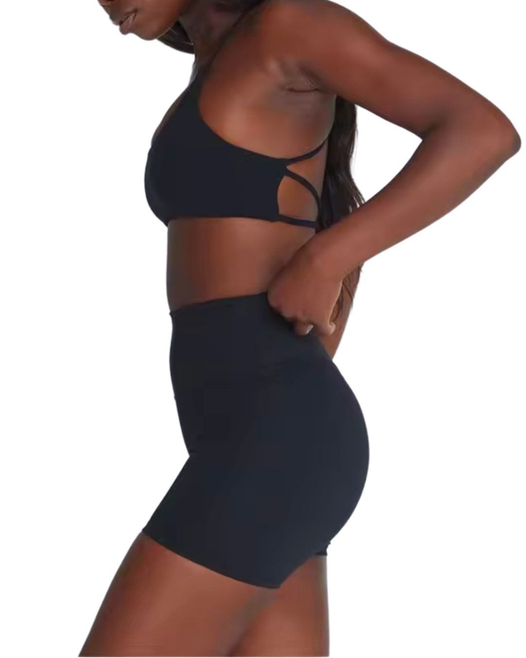 Woman wearing black ORU CROSSOVER SPORTS BRA with seamless design, strappy back, and matching high-waisted shorts.