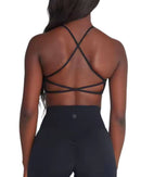 Back view of woman wearing ORU crossover sports bra with thin crisscross straps and light support underband in black.